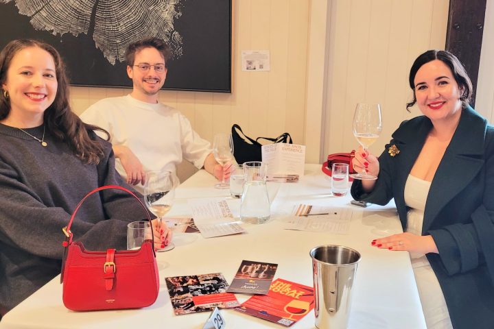 Three people at a table with drinks and menus, smiling indoors.