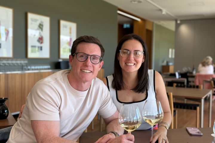Smiling couple in a restaurant sitting at a table with wine glasses.