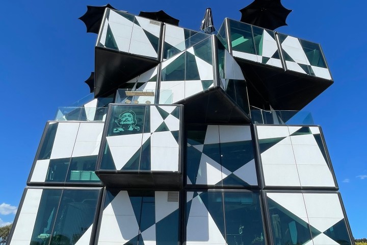 Modern building with geometric pattern and large glass panels against clear blue sky.