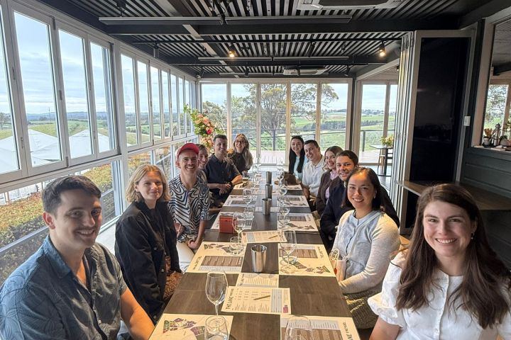 Group of people seated at a long table with menus and glasses in a bright room.