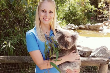a woman holding a koala posing for the camera