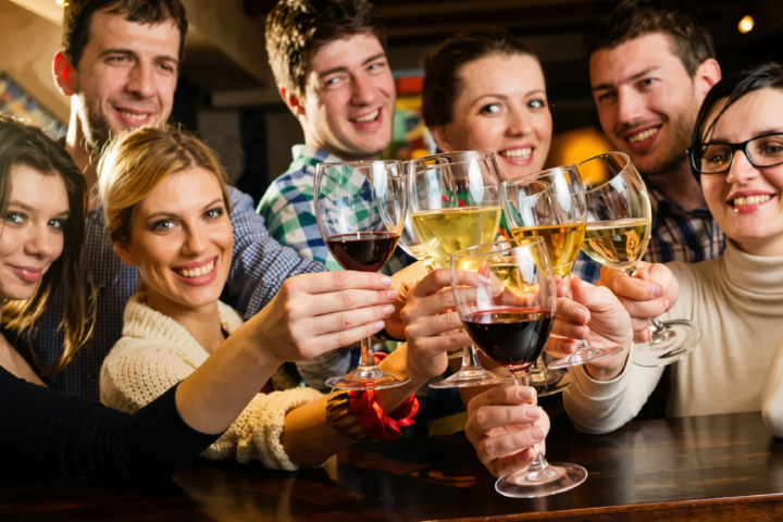 Group of smiling people toasting with wine glasses in a bar.