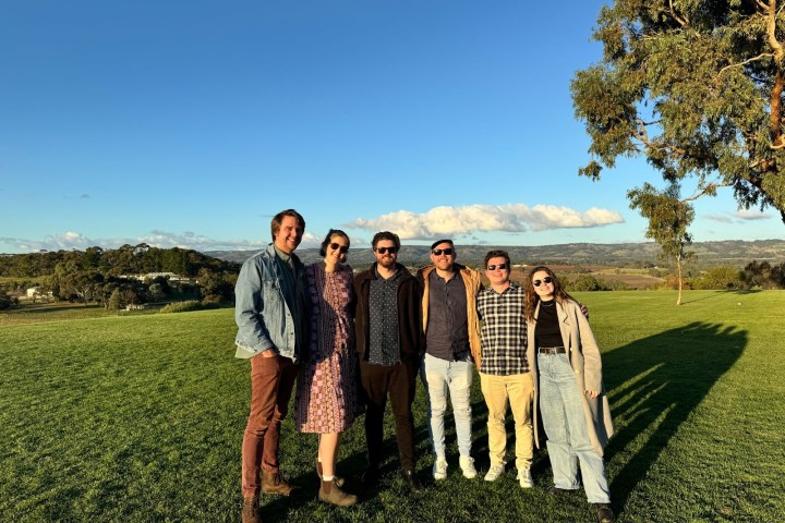 a group of people standing in a grass field posing for the camera