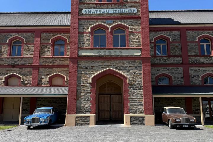 Historic stone building labeled 'Chateau Tanunda' with vintage cars parked out front.